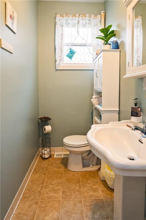half bathroom with tile patterned floors, toilet, and visible vents