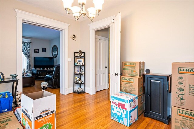 interior space featuring light wood-style floors, baseboards, and an inviting chandelier