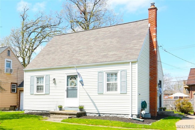 rear view of house featuring a yard, cooling unit, a shingled roof, and a chimney