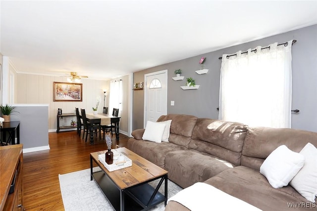 living area featuring baseboards, ceiling fan, and wood finished floors