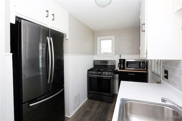 kitchen with freestanding refrigerator, a sink, gas stove, and white cabinets