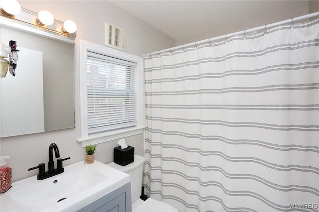 bathroom featuring vanity, a shower with shower curtain, toilet, and visible vents