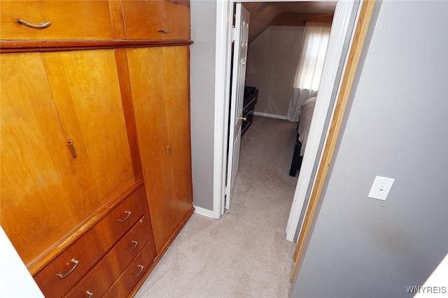 corridor with light colored carpet, baseboards, and lofted ceiling