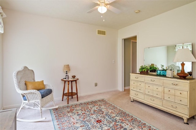 living area with baseboards, ceiling fan, light colored carpet, and visible vents