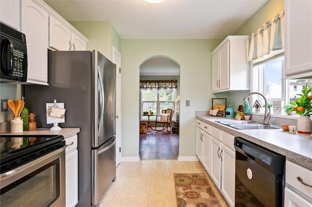kitchen with a sink, white cabinetry, arched walkways, and black appliances