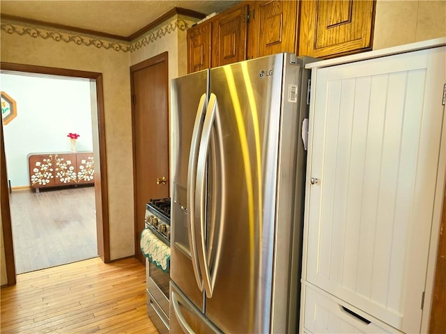 kitchen featuring crown molding, stainless steel appliances, brown cabinetry, and light wood-type flooring