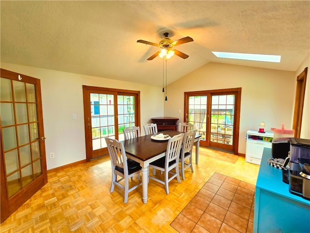 dining space featuring a healthy amount of sunlight, ceiling fan, lofted ceiling with skylight, and a textured ceiling