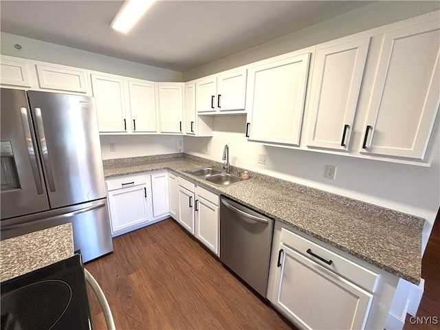 kitchen with a sink, stone countertops, stainless steel appliances, white cabinetry, and dark wood-style floors
