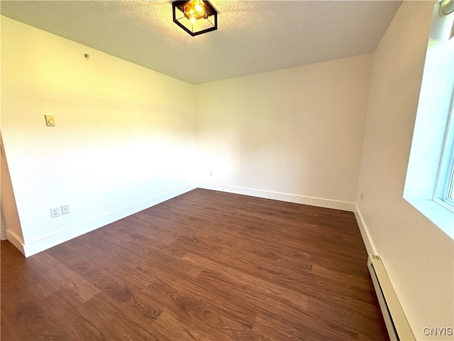 spare room featuring baseboards, a baseboard radiator, and dark wood-style floors
