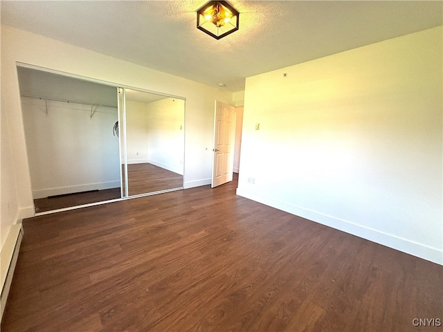 unfurnished bedroom with baseboards, a baseboard radiator, a closet, and dark wood-type flooring