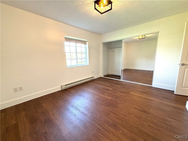 unfurnished bedroom featuring baseboards, a baseboard heating unit, a closet, and wood finished floors