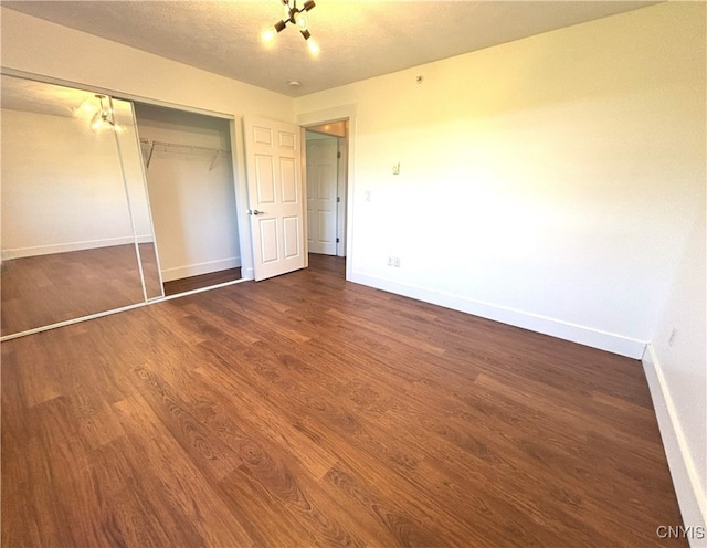 unfurnished bedroom with baseboards, wood finished floors, and a closet
