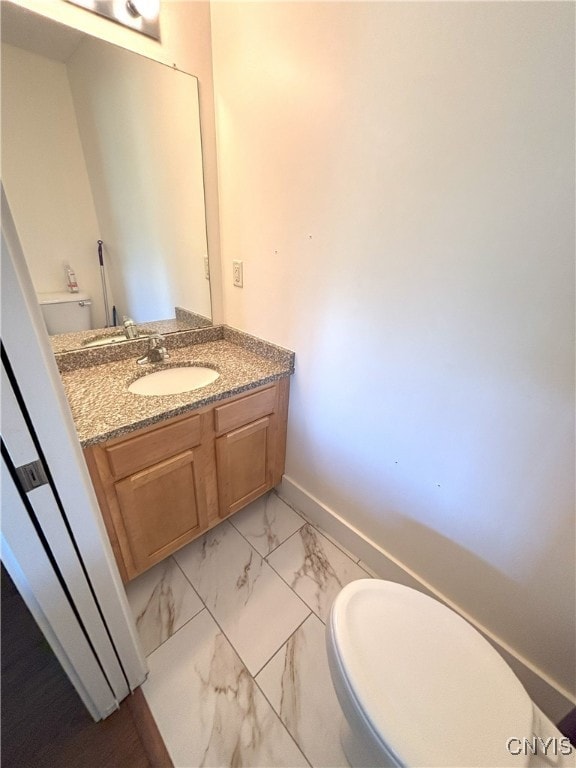bathroom featuring baseboards, vanity, toilet, and marble finish floor