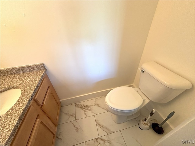 half bathroom with baseboards, vanity, toilet, and marble finish floor