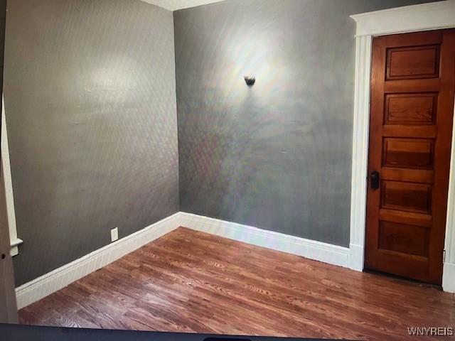 empty room with baseboards and wood finished floors