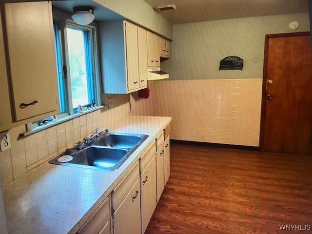 kitchen with a sink, light countertops, dark wood-style flooring, and visible vents