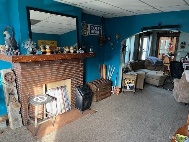 carpeted living area with a drop ceiling and a fireplace