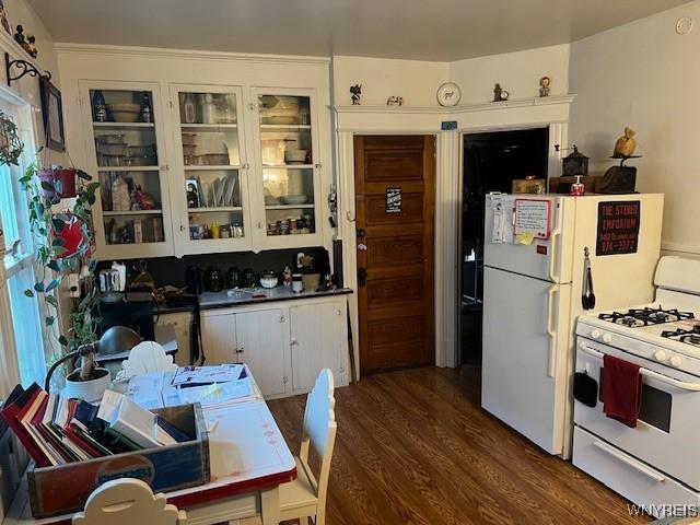 kitchen featuring wood finished floors, white appliances, and glass insert cabinets