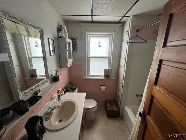 full bath featuring vanity, tile patterned flooring, toilet, a drop ceiling, and shower / washtub combination
