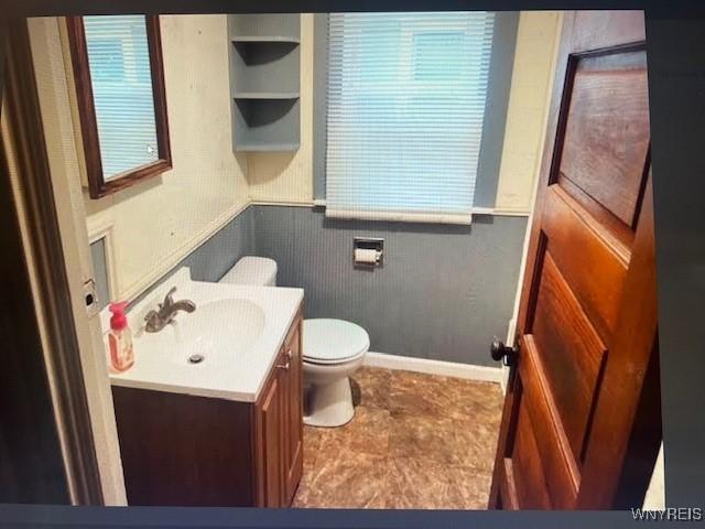 bathroom featuring vanity, a wainscoted wall, and toilet