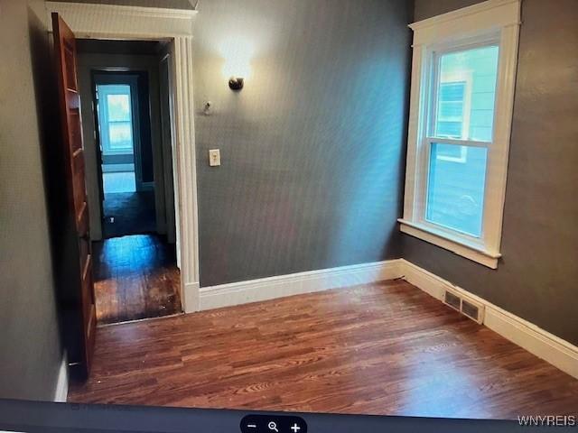 spare room featuring baseboards, wood finished floors, and visible vents