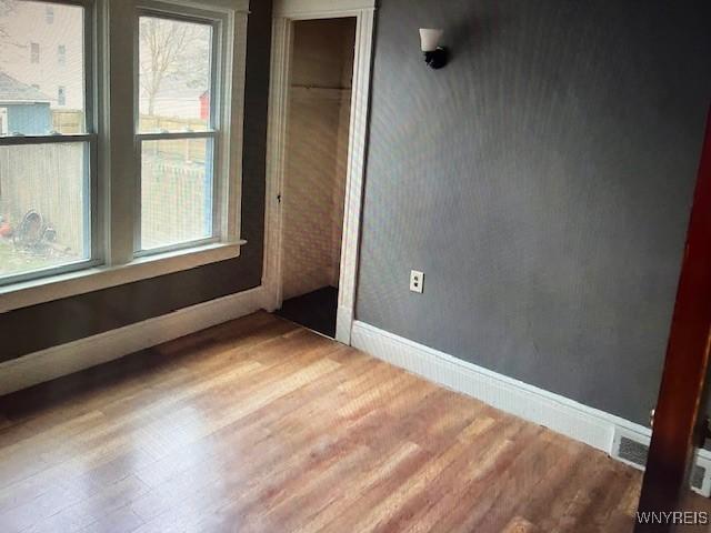 spare room featuring baseboards and wood finished floors