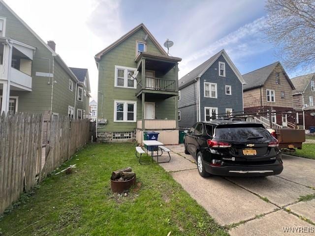 rear view of property featuring fence and a lawn