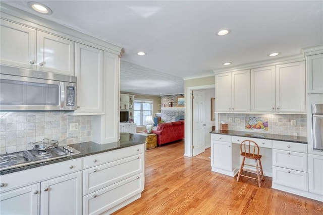 kitchen with open floor plan, appliances with stainless steel finishes, backsplash, and white cabinets