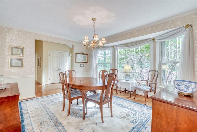 dining space featuring crown molding, light wood-style flooring, a chandelier, and wallpapered walls