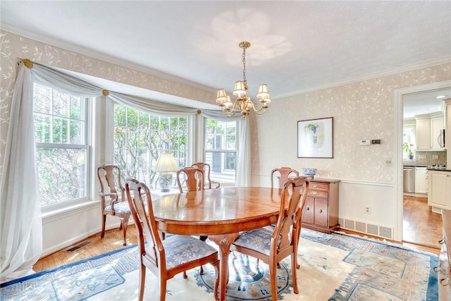 dining area with visible vents, a notable chandelier, a wealth of natural light, and wallpapered walls