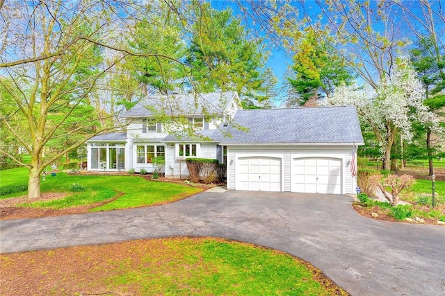 view of front facade with aphalt driveway, a front lawn, and a garage