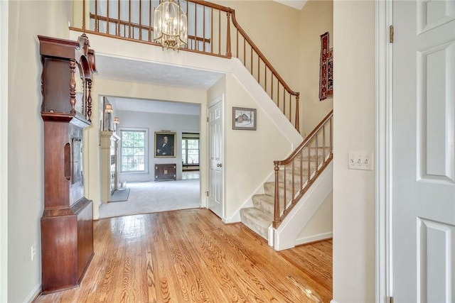 foyer with baseboards, stairs, wood finished floors, and a notable chandelier