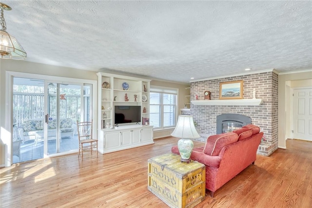 living area featuring a brick fireplace, a textured ceiling, and light wood-type flooring