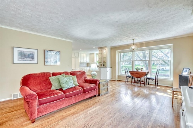 living room with a textured ceiling, visible vents, and baseboards