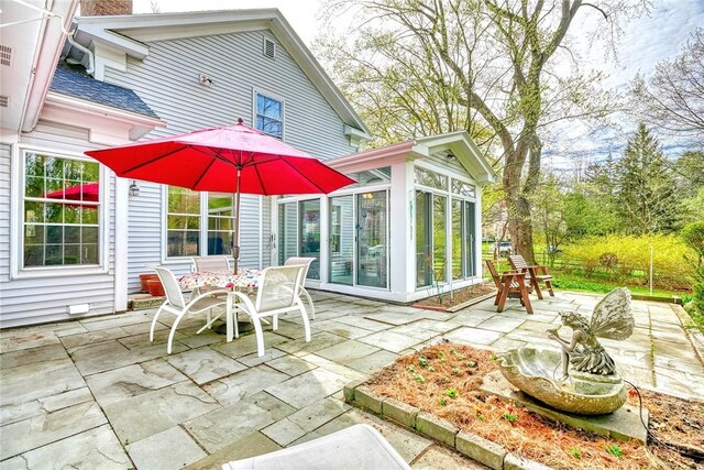 view of patio / terrace with outdoor dining space and a sunroom