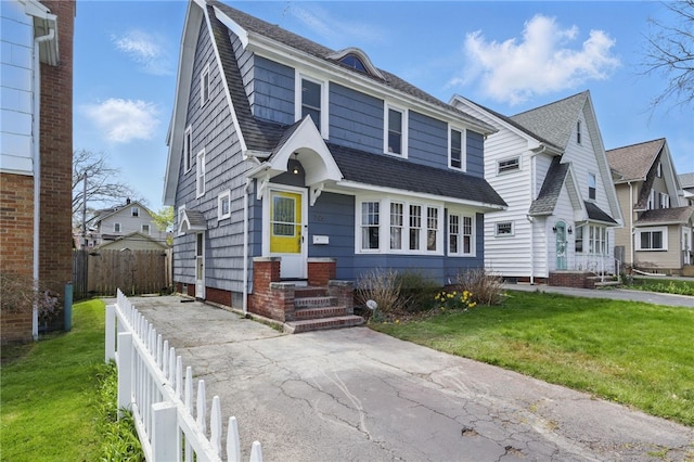 view of front of house featuring fence, a shingled roof, and a front yard