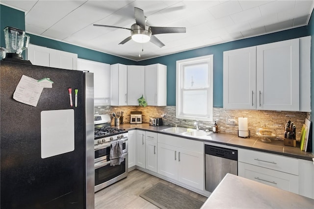 kitchen featuring ceiling fan, backsplash, appliances with stainless steel finishes, a sink, and white cabinets