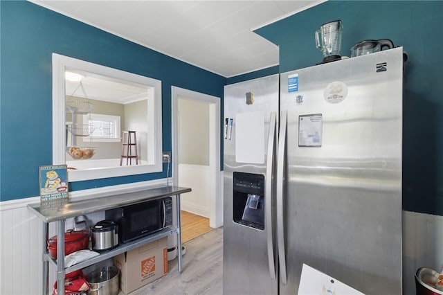 kitchen featuring stainless steel fridge, a wainscoted wall, and wood finished floors