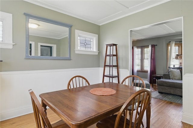 dining space with ornamental molding, wainscoting, and wood finished floors