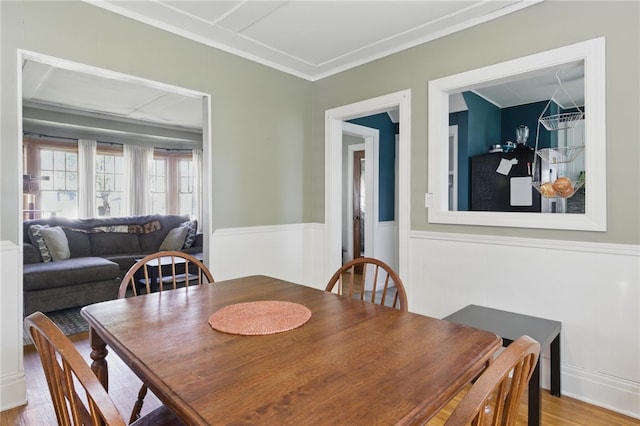 dining room with crown molding, wainscoting, and wood finished floors