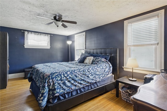 bedroom with a ceiling fan, a textured ceiling, and wood finished floors