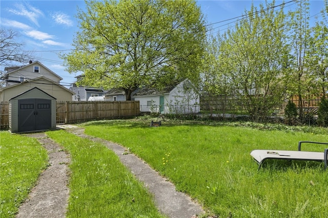 view of yard featuring an outdoor structure, a fenced backyard, and a shed