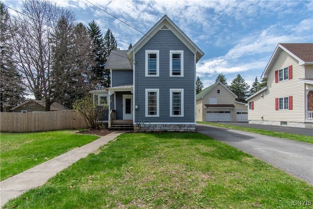 view of front facade with fence, a detached garage, an outbuilding, and a front yard