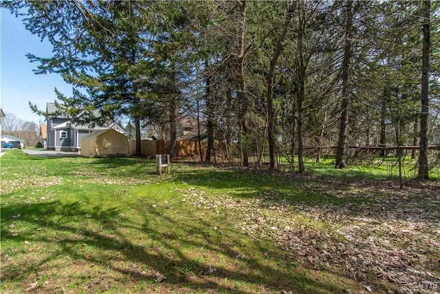 view of yard with an outdoor structure, a shed, and fence