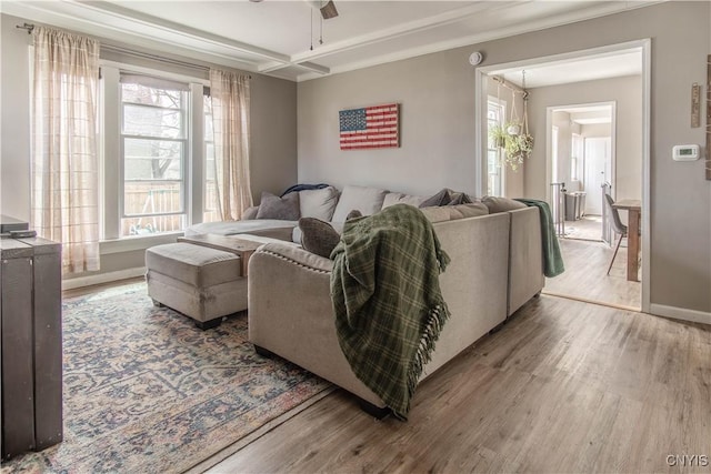 living area with a ceiling fan, baseboards, and wood finished floors