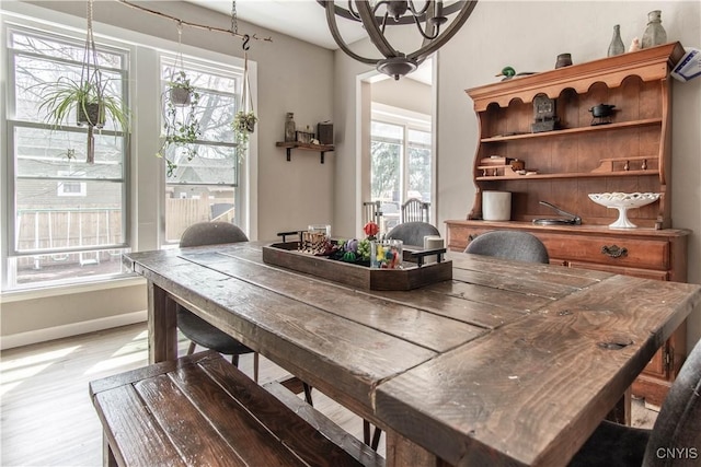 dining space featuring baseboards, an inviting chandelier, and light wood-style floors