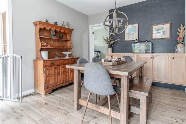 dining space with an inviting chandelier, light wood-style floors, and washer / clothes dryer