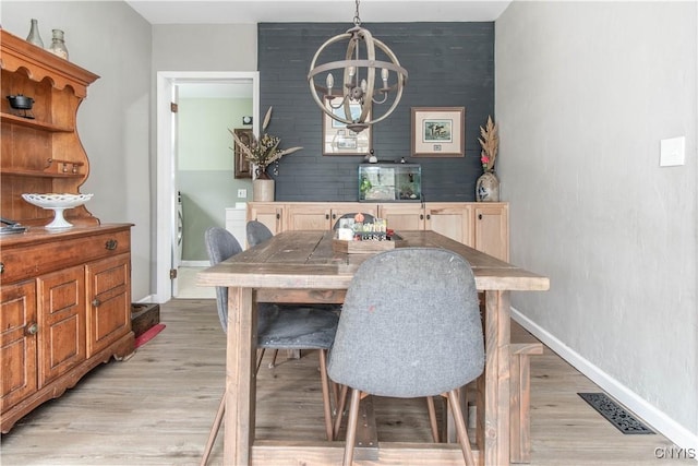 dining room with an inviting chandelier, baseboards, light wood-style floors, and visible vents