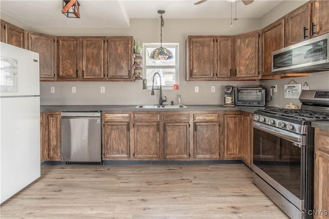 kitchen with a sink, a toaster, a ceiling fan, light wood-style flooring, and appliances with stainless steel finishes