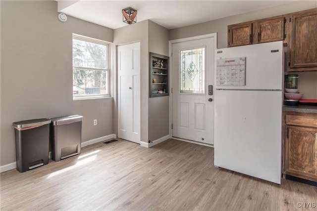 doorway to outside with baseboards, light wood-type flooring, and visible vents